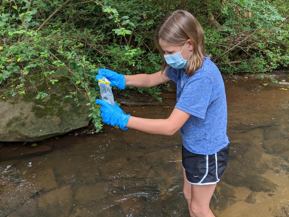 A volunteer taking a bacterial sample with a mask on.